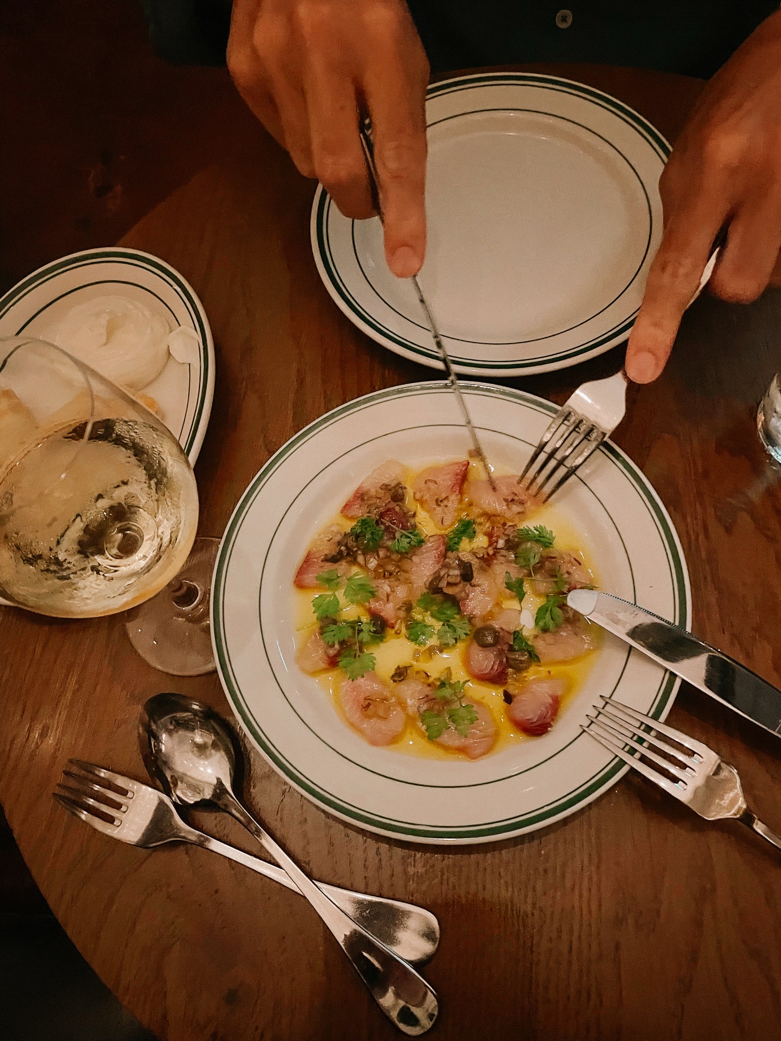 Photo d'une assiette de carpaccio de Saint Jacques avec un verre de vin blanc.